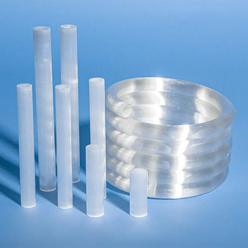 Collection of opaque milky quartz tubes alongside a large milky quartz spiral tube coil, on a blue background.
