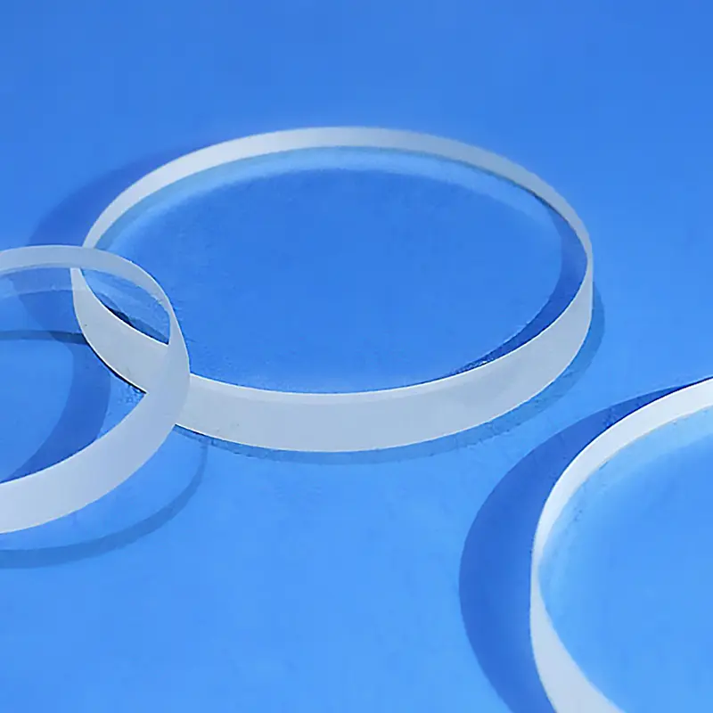 Several clear circular quartz sight glass rings and discs displayed together.