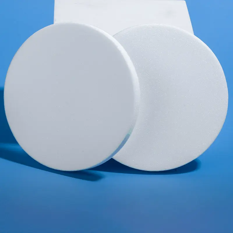 Close-up of two large white sintered quartz discs, highlighting their porous surface texture, on blue