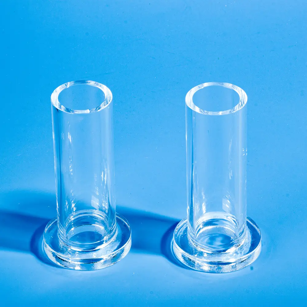 Pair of clear flanged quartz tubes standing upright, showing the tube body and flange base