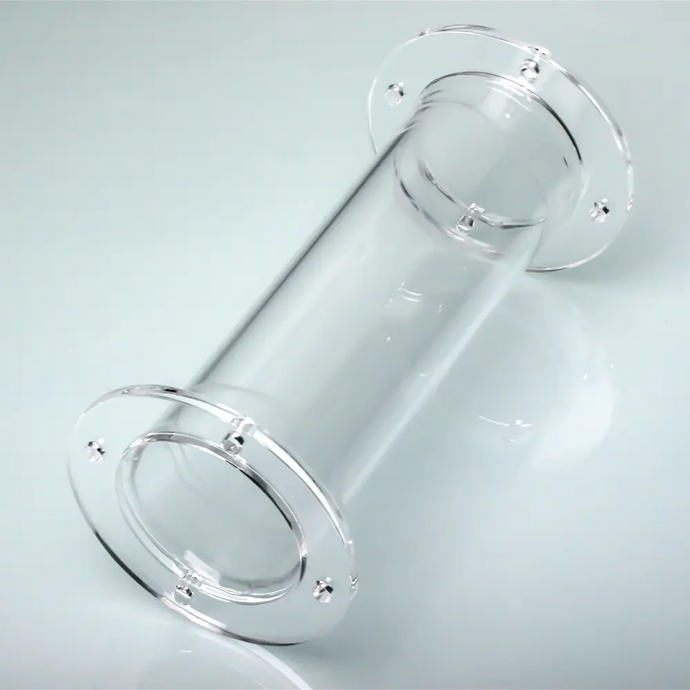 Clear quartz tube with flanges on both ends, angled view on a light grey reflective surface