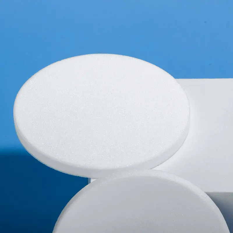 Edge view of a white porous quartz filter disc resting on a white support, showcasing its thickness