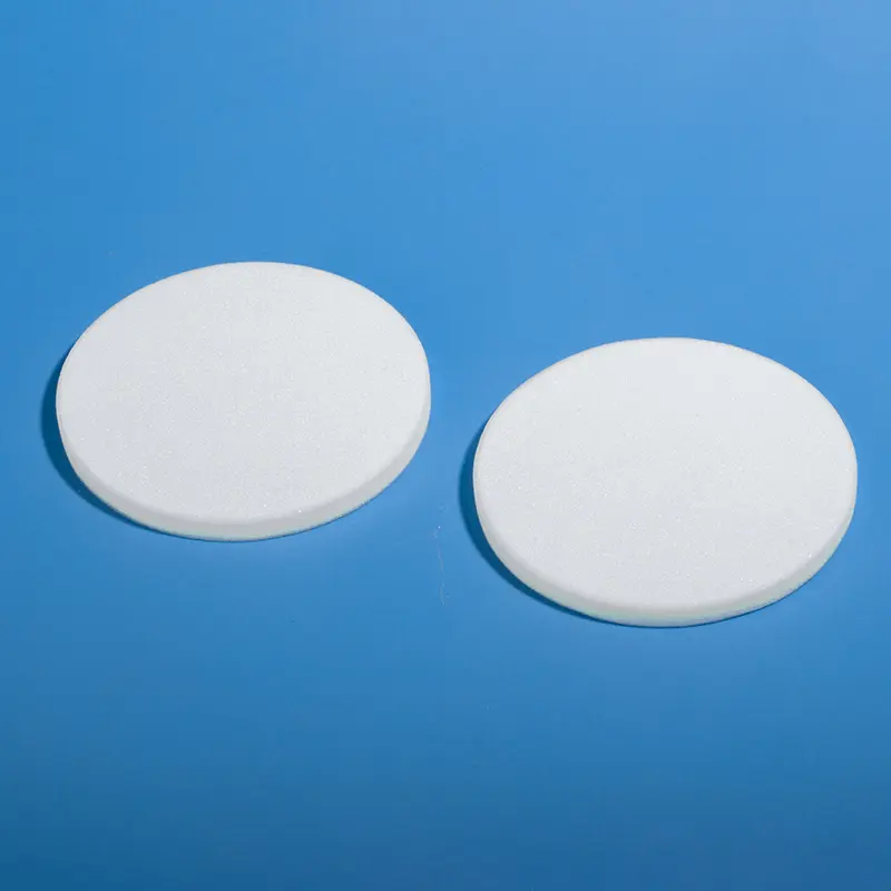 Pair of white quartz fritted discs (sintered plates) laid flat on a blue surface