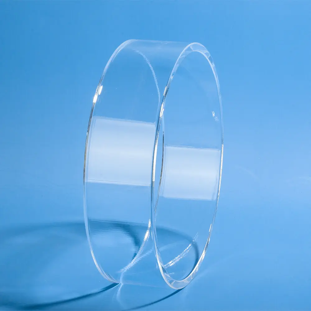 Side view of a clear, polished quartz glass ring standing on edge against a blue background